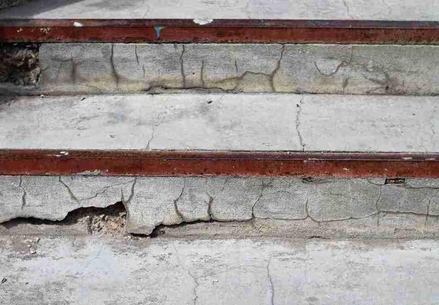 Cracked and damaged concrete steps with visible surface erosion and exposed edges.